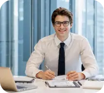 Man wearing glasses and white shirt with laptop and papers.