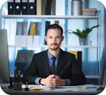 Person in black suit at table, front view.