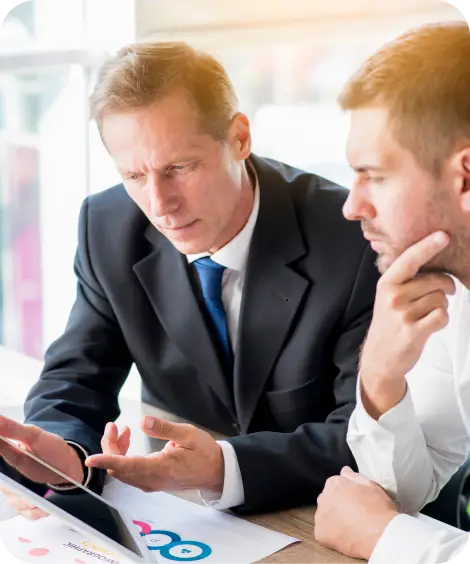 Two men at desk with graphs.